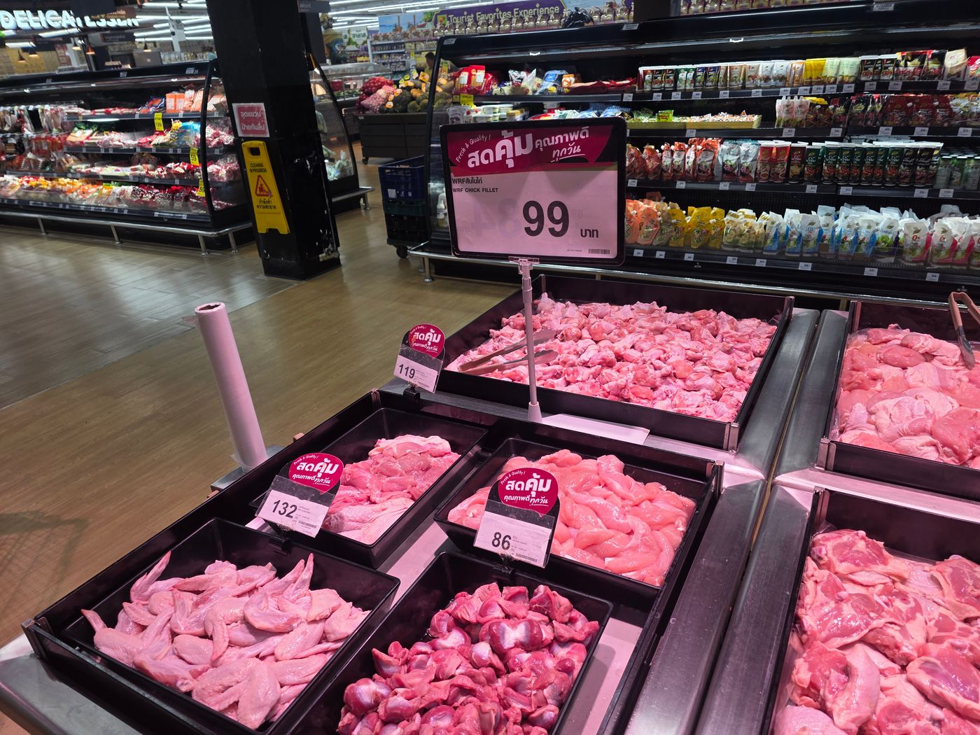 A Thai supermarket chicken counter photographed by Danny Flight with a 99 baht per kilo sign for chicken fillet and tray tags at 86, 119, and 132 baht.