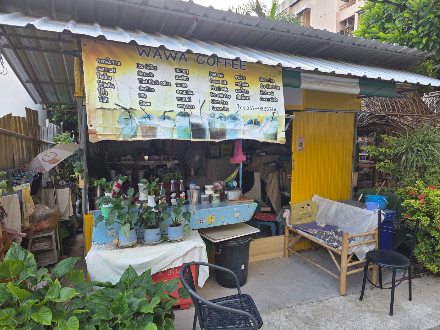 A small yellow street coffee stall in Pattaya with a hand-painted menu banner in Thai and English, photographed by Danny Flight.