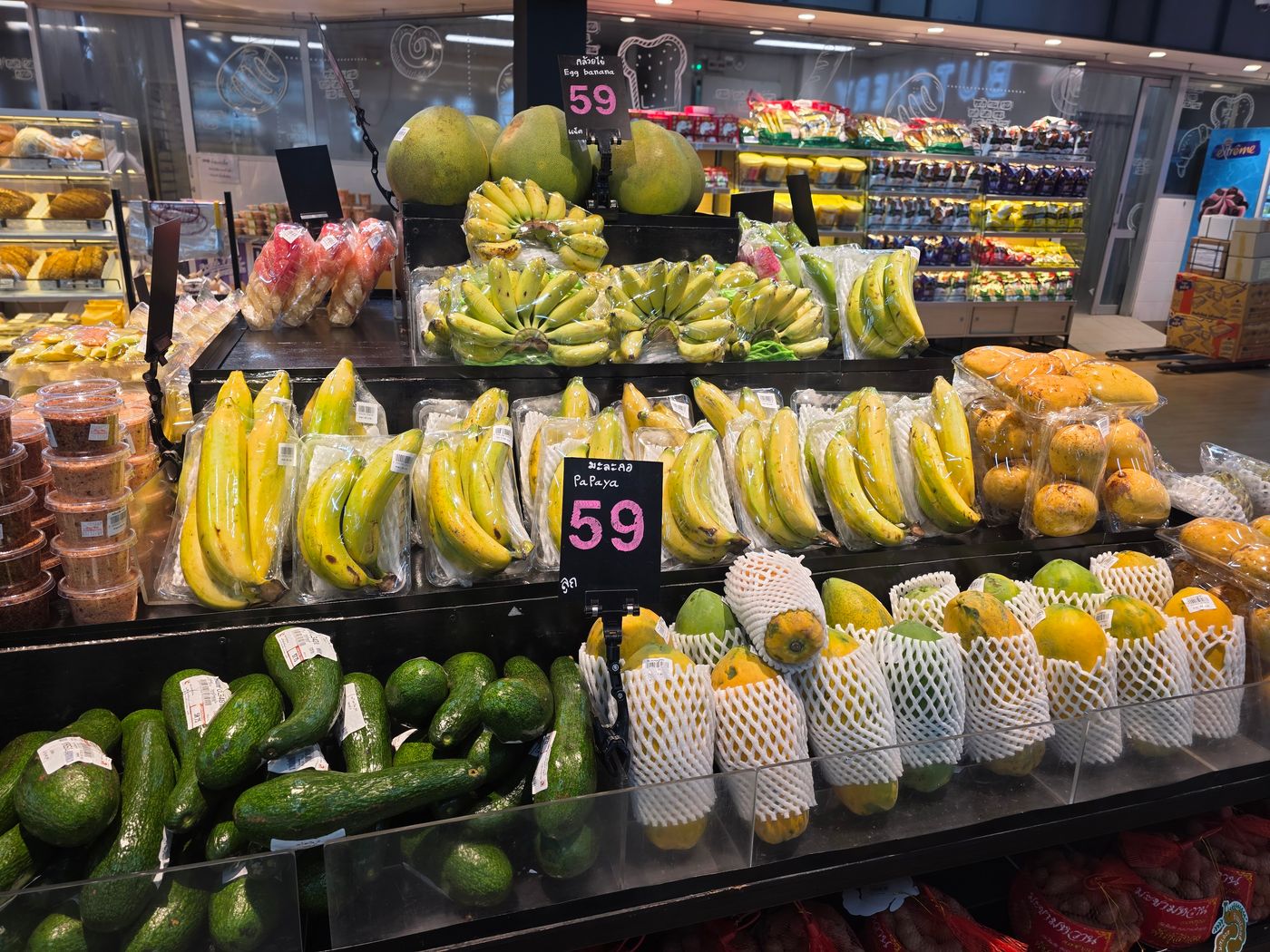 A Thai supermarket fruit display photographed by Danny Flight with bananas and papaya priced at 59 baht on handwritten signs.