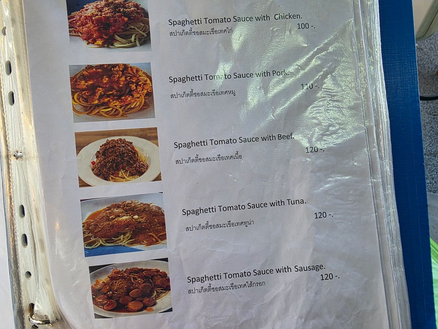 A Thai restaurant menu page photographed by Danny Flight listing spaghetti with chicken at 100 baht, pork 110, beef, tuna, or sausage 120.
